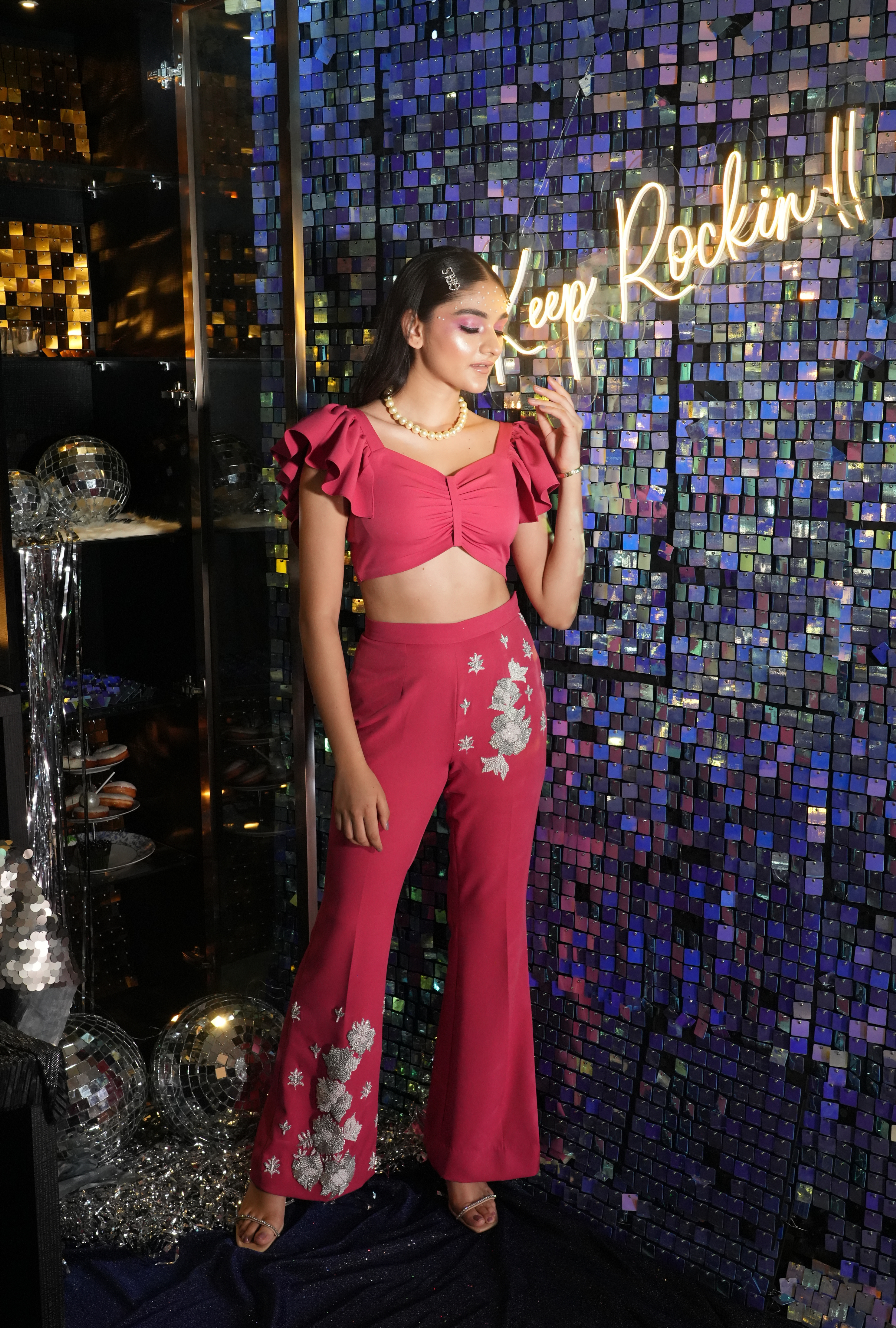 Woman wearing fuchsia pink coord set with ruffled sleeves and silver embroidery by Prisella