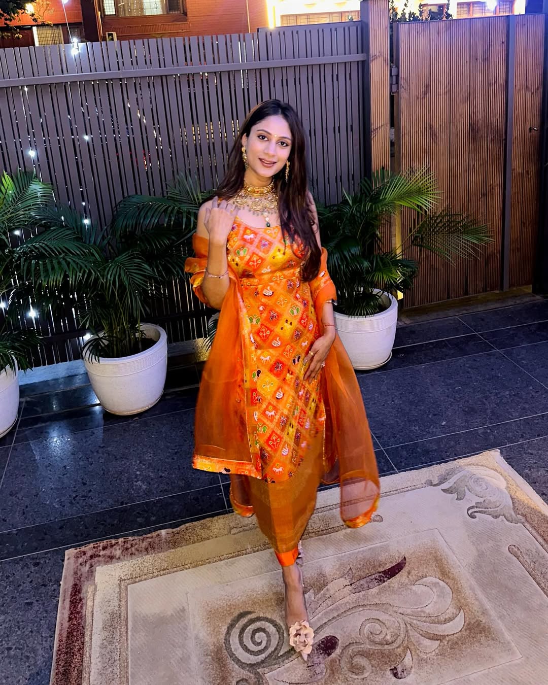 Model dressed in a vibrant orange Indian salwar suit with jari detailing—perfect for Rakhi, Haldi, or festive wear.