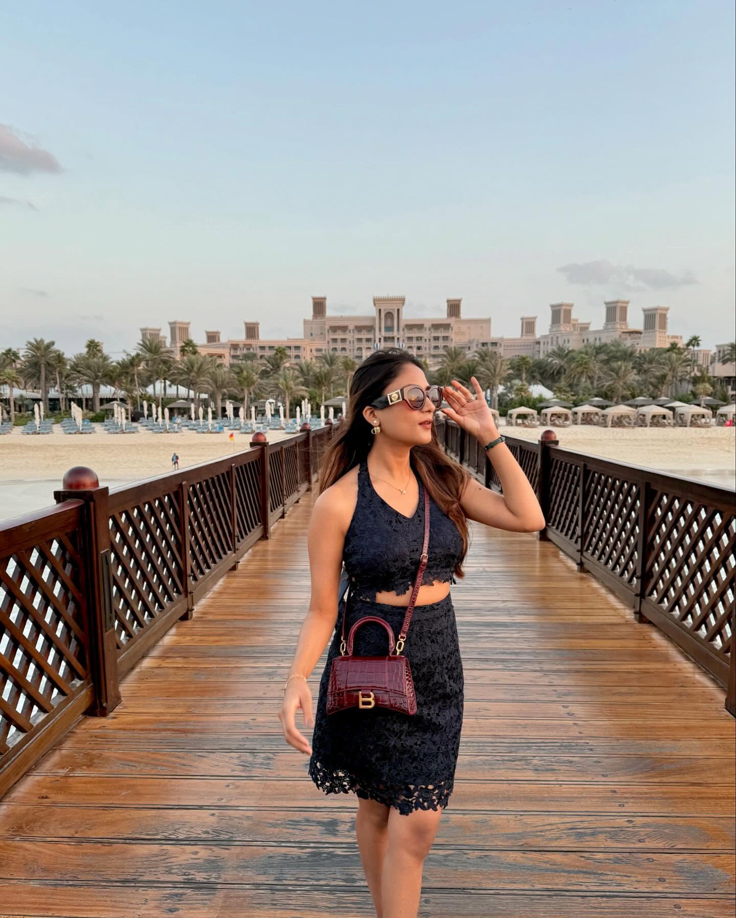 Woman wearing navy lace halter crop top and mini skirt co-ord set at a beach boardwalk – Prisella occasion vacation outfit