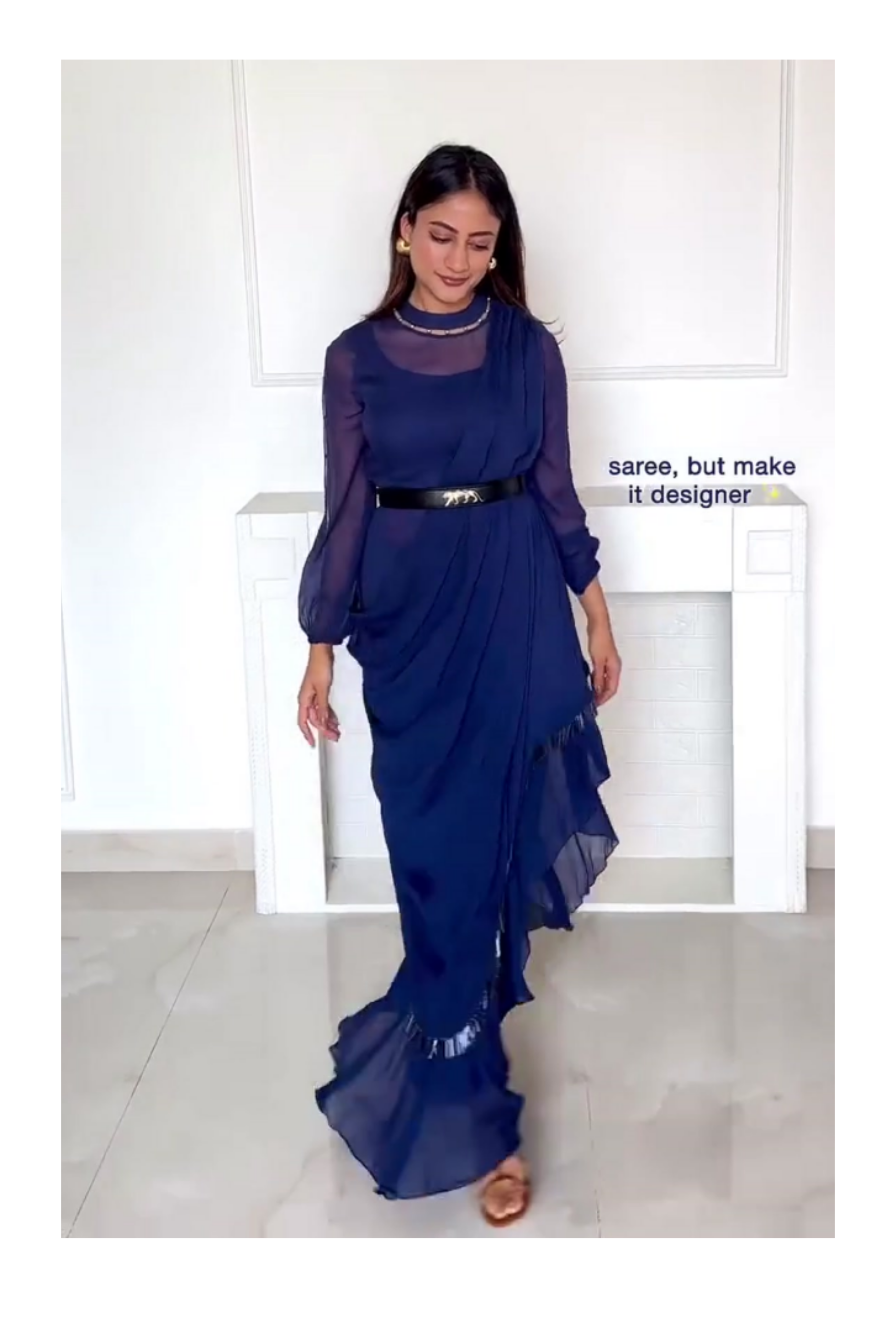 Model wearing a navy blue pre-draped ruffle saree and designer blouse with sheer sleeves and a statement belt, ideal for modern festive evenings.